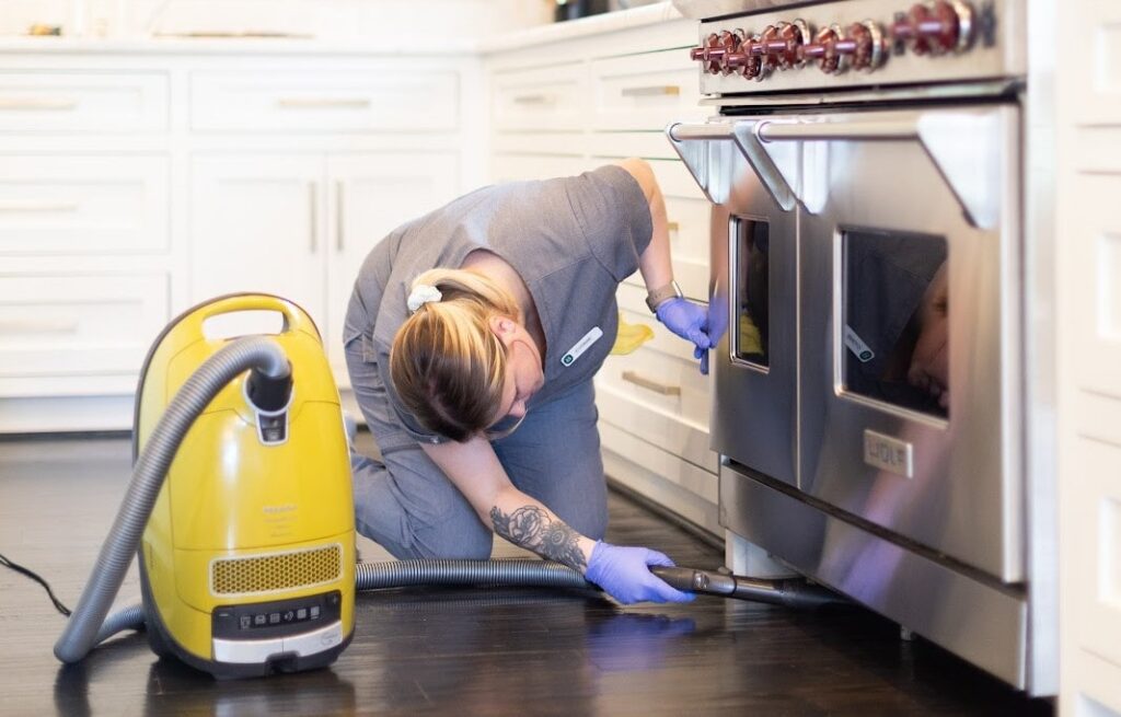 A professional cleaner vacuuming under a microwave A professional cleaner vacuuming under a microwave, demonstrating how to clean your microwave effectively and maintain a tidy kitchen