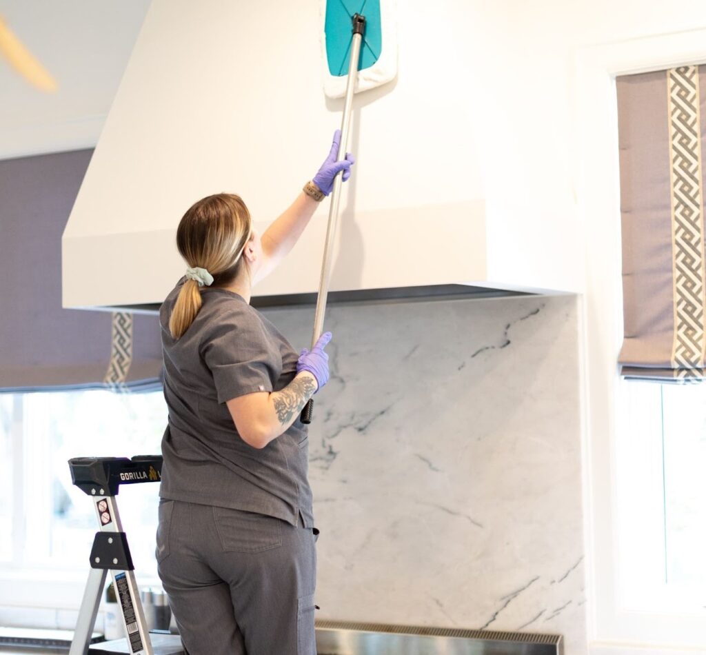 "Cleaner using a microfiber mop to clean a kitchen hood, "Cleaner using a microfiber mop to clean a kitchen hood, showcasing tips for efficiently cleaning your kitchen."