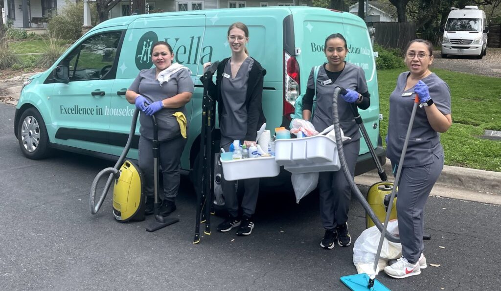 Four professional cleaners from Vella are holding their tools, and there is a van behind them.