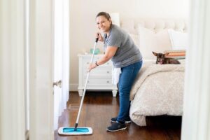 A Vella cleaning professional mops a wooden floor using a Sh-mop scrubber, designed for safe and slip-free cleaning.