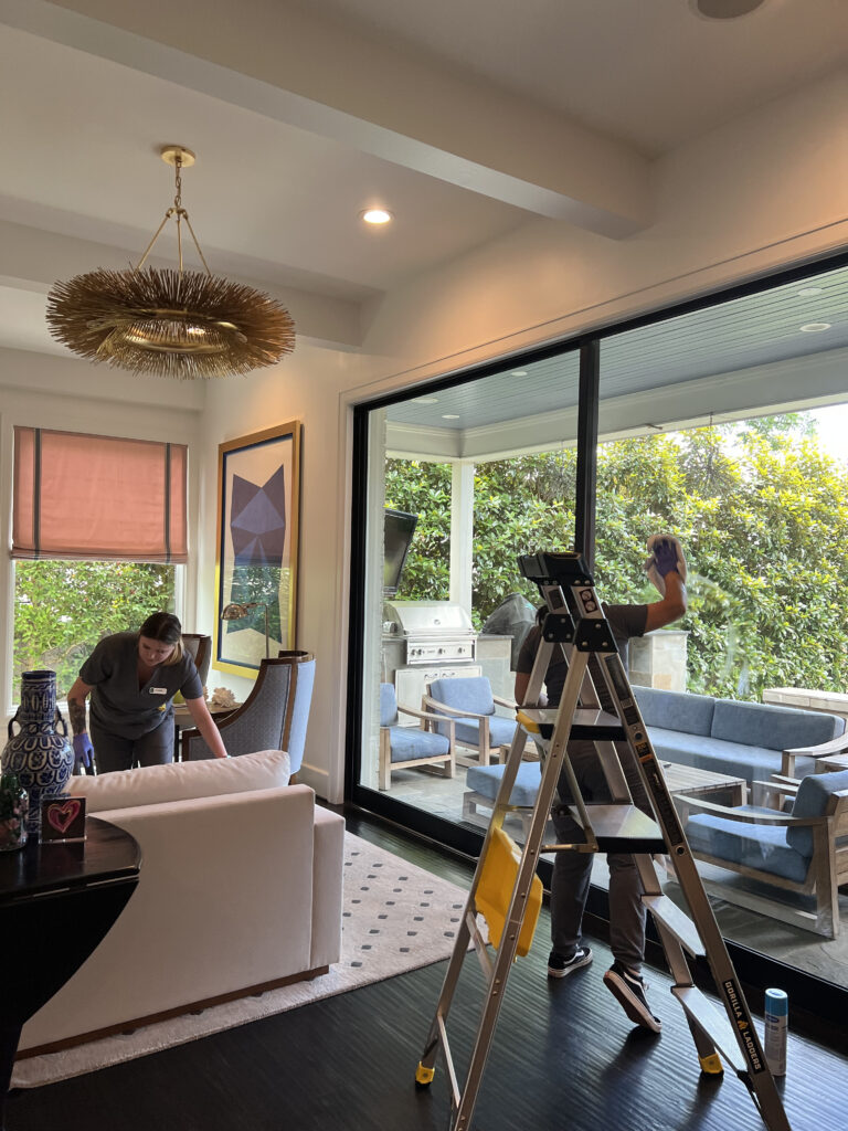 Vella staff cleaning a glass wall and a sofa set inside a home in Dallas.