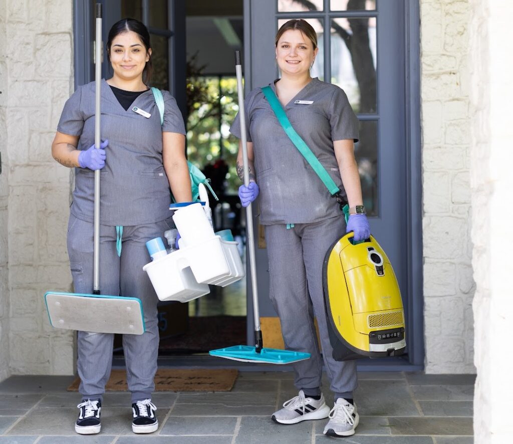 Two house cleaners in uniforms holding cleaning supplies Two house cleaners in uniforms holding cleaning supplies and a vacuum, ready for house cleaning with pets.