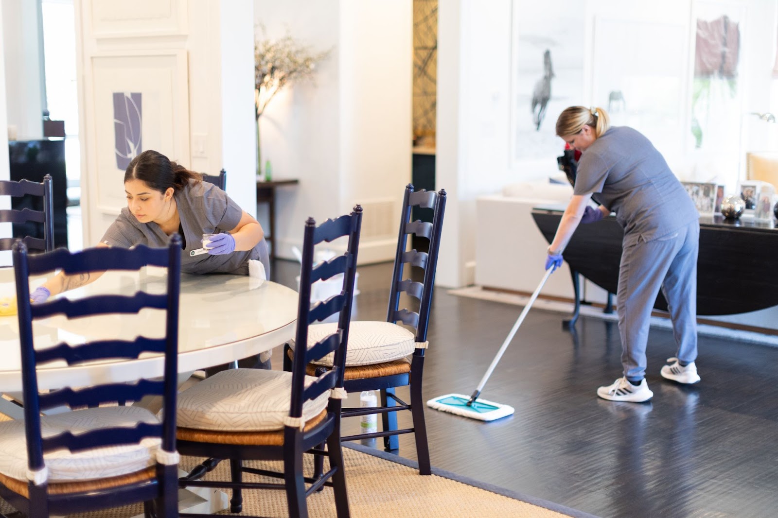 Two professional cleaners Two professional cleaners working in a modern home – one wiping down countertops and surfaces, while the other mops the floor for a spotless finish.