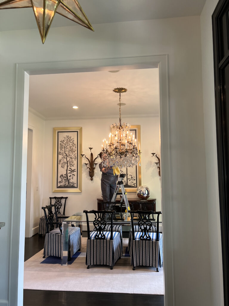 Vella cleaner on ladder deep cleaning a chandelier in a Dallas home, ensuring top-to-bottom shine.